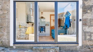A modern interior with a kitchen, a blue sofa, and a dining area. - Pipedream (Porthleven)