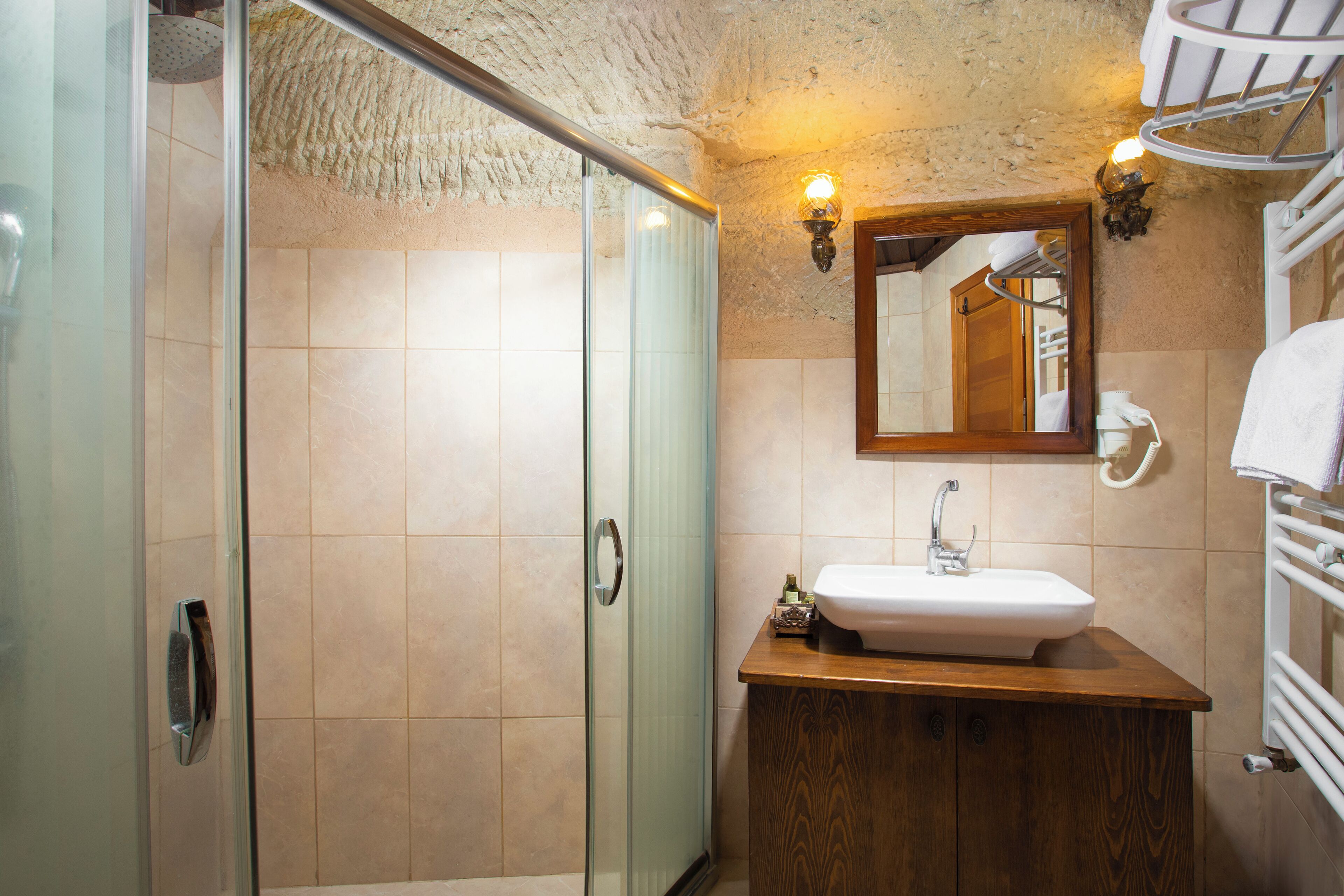 A bathroom with a glass shower door, a wooden vanity with a sink, and a mirror above the sink.