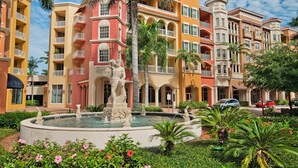 A hotel courtyard with a central fountain, palm trees, and a statue. - Location and Lifestyle at its Finest! (Naples)