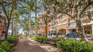 A paved walkway lined with trees and benches, leading to a building with a visible sign for 'Phenix Salon Suites'. - Location and Lifestyle at its Finest! (Naples)