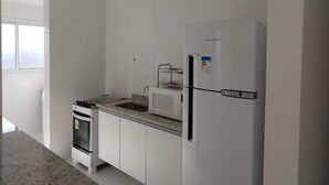 Eine moderne Küche mit weißen Schränken, einem eingebauten Ofen, einer Mikrowelle und einem Kühlschrank.