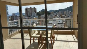 Ein Balkon mit Tisch und Stühlen, der einen Blick auf eine Stadt mit Gebäuden und Hügeln bietet.