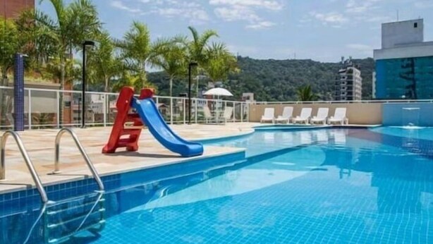 Ein Schwimmbecken mit einer blauen Rutsche und weißen Liegestühlen.