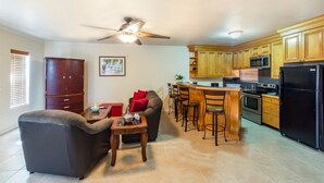 A modern kitchen with wooden cabinets, a black refrigerator, and a bar area with stools. - Caicos Cactus Residence  Major Hill (Caicos Islands)