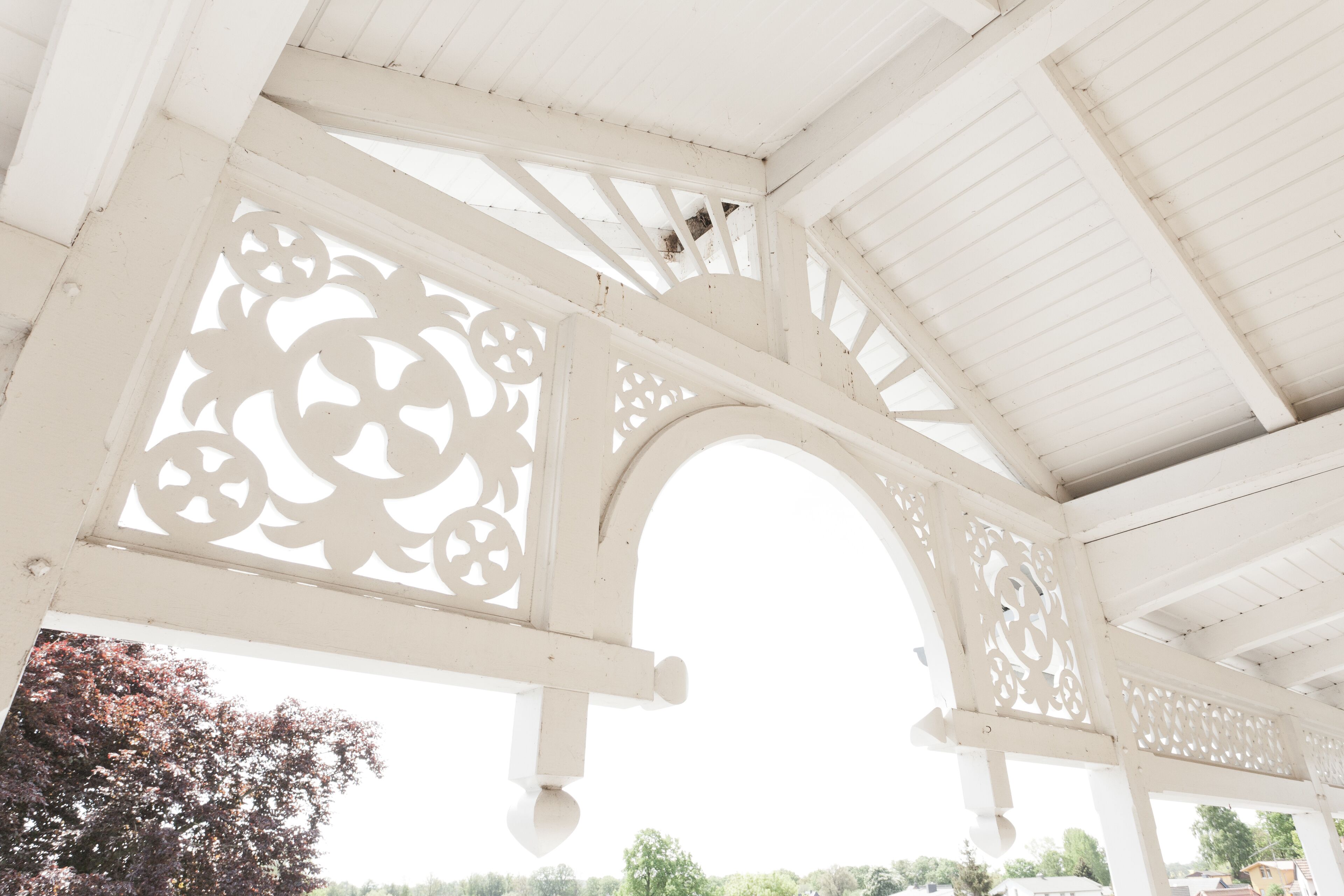 A white wooden structure with intricate cut-out designs and an arched opening.