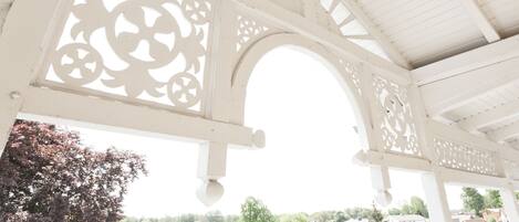 A white wooden structure with intricate cut-out designs and an arched opening.