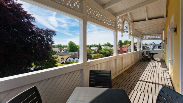 A covered outdoor area with a table and chairs, overlooking a residential neighborhood. - Haus Sonne (Sellin)