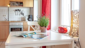 A kitchen with wooden cabinets, a white countertop, a coffee maker, a red speaker, and a potted plant. - Haus Sonne (Sellin)