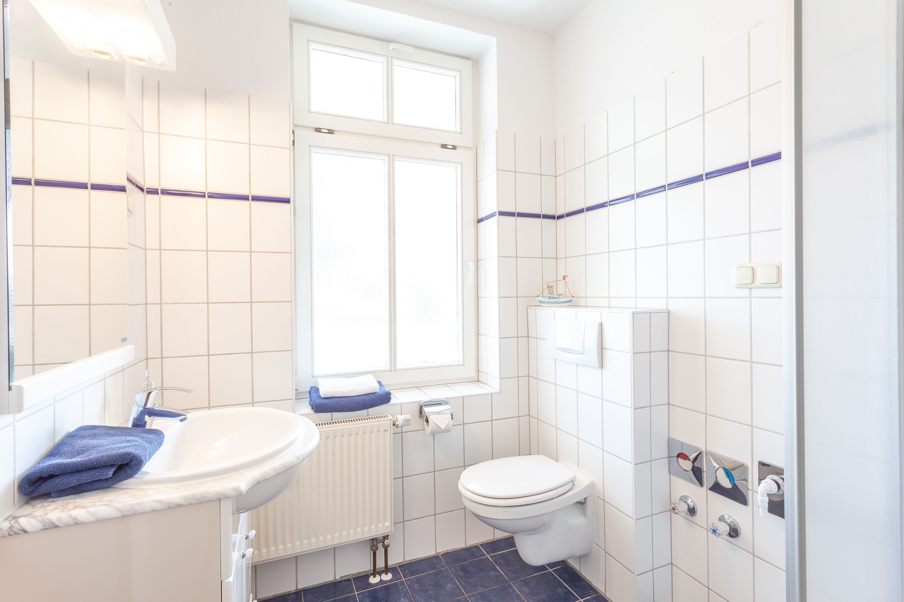 A bathroom with a white sink, a toilet, and a window.