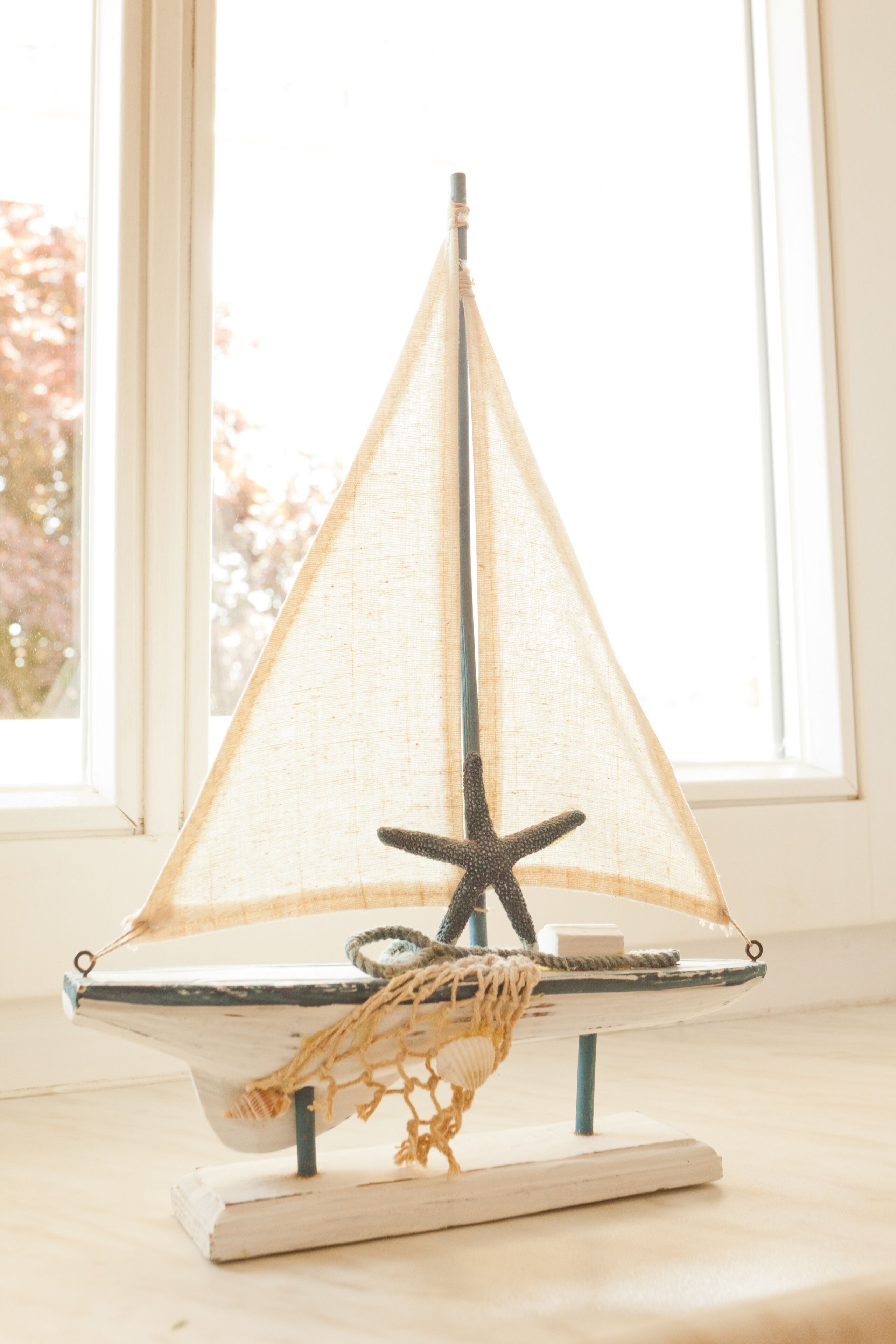 Un velero modelo con un adorno de estrella de mar, sobre una base de madera.