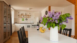 A dining table with a vase of flowers, a bottle of wine, and fruit. - Haus Sonne (Sellin)