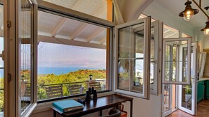 Una habitación con un amplio ventanal que ofrece una vista panorámica del mar y la vegetación.