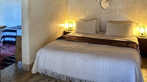 A bedroom with a wooden ceiling, a bed with white bedding, two bedside lamps, and decorative wall mirrors. - Dar Rafti (Fes)