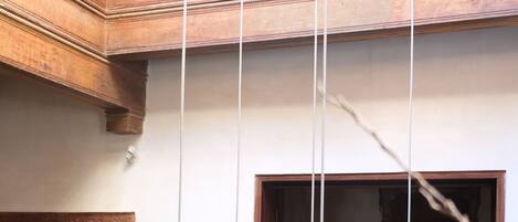 Una habitación tradicional con balcón de madera, ventana con vistas y lámparas colgantes tejidas.