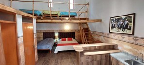 A dormitory room with bunk beds, a small kitchenette, and a staircase leading to an upper bunk. - Hostería Caballeriza Tradición Colca (Yanque)