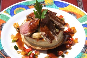 A plate of food with a variety of vegetables and meat, garnished with a leaf. - Hostería Caballeriza Tradición Colca (Yanque)