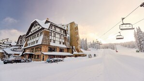 Un edificio cubierto de nieve con un telesilla al fondo.
