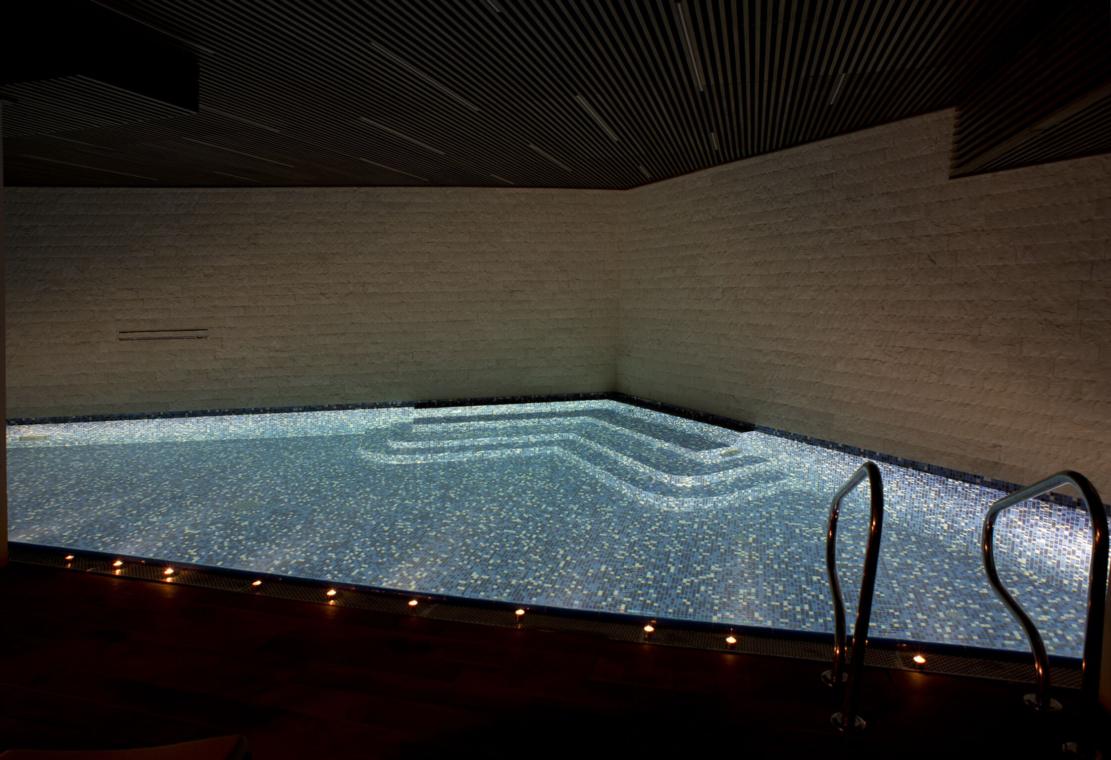 A large indoor swimming pool with a tiled floor and a dark ceiling.