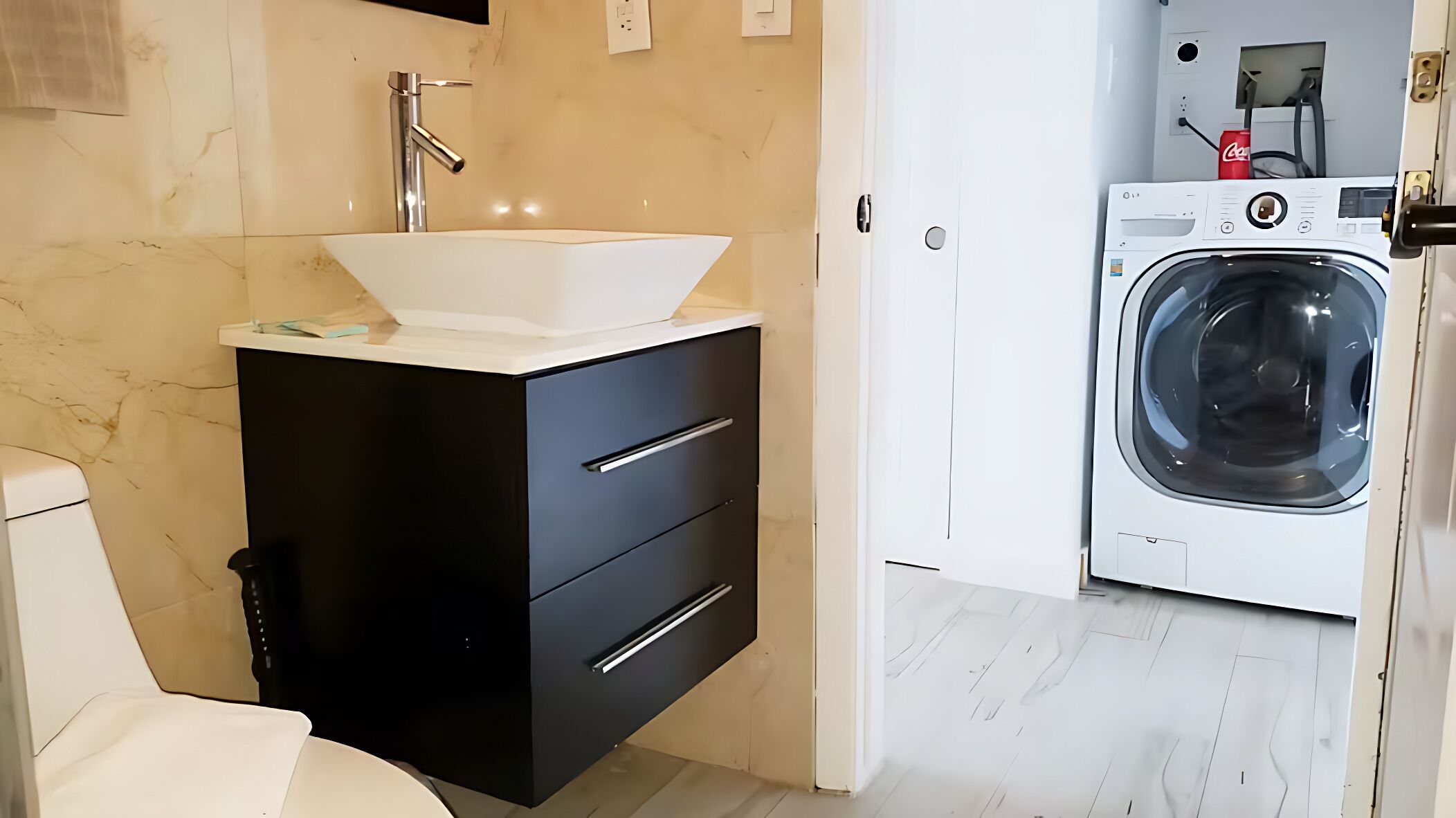 A compact bathroom with a white sink, black cabinet, and a washing machine.