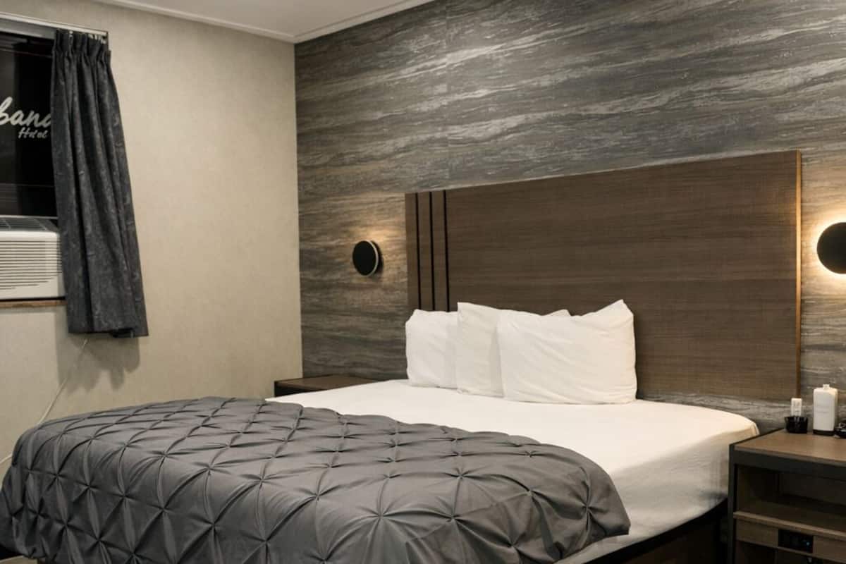 Un dormitorio moderno con una cama grande, cabecera de madera y mesita de noche integrada.