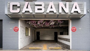 A building entrance with the sign "CABANA" above, two stop signs, and a speed bump ahead. - Cabana Hotel Yankee Stadium (Bronx)