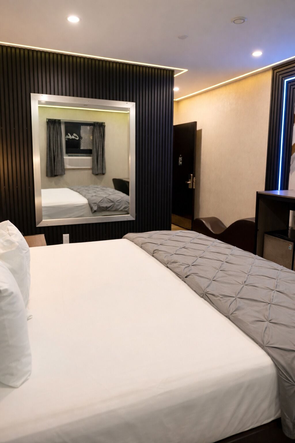 Una habitación de hotel con una cama grande, un espejo, un escritorio y un armario.