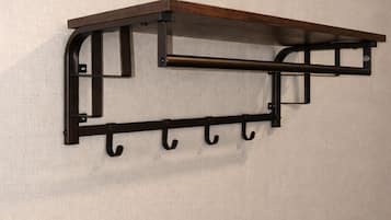 A wall-mounted metal shelf with hooks.