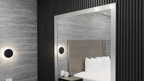 A modern hotel room with a large bed, a bedside table, a nightstand, and a wall-mounted mirror. - Cabana Hotel Yankee Stadium (Bronx)