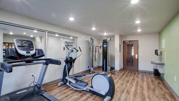 Un gimnasio con cintas de correr, elípticas y máquinas de pesas.
