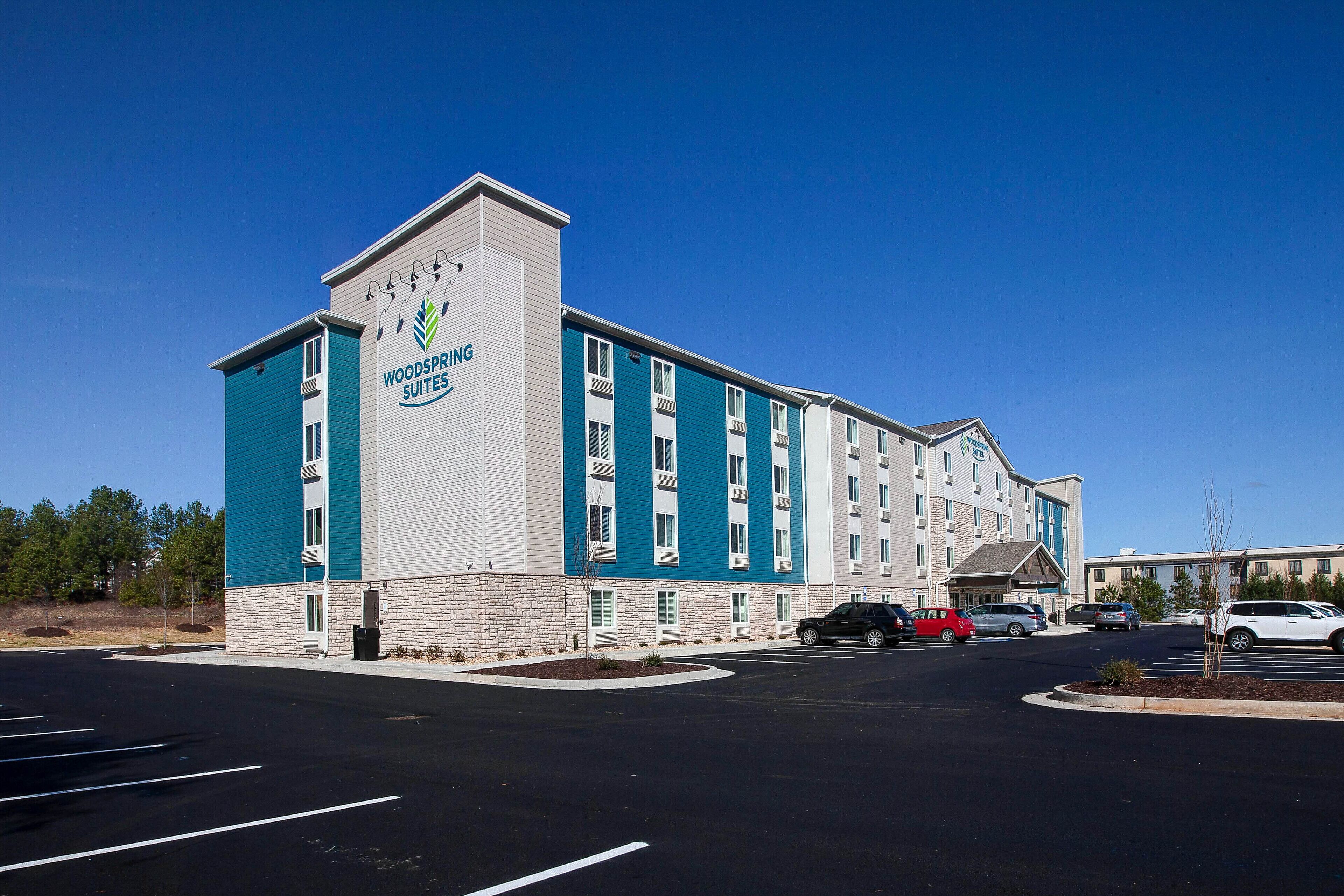 A multi-story hotel with a prominent sign reading "Woodspring Suites."