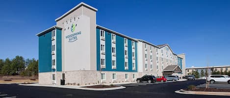 A multi-story hotel with a prominent sign reading "Woodspring Suites."