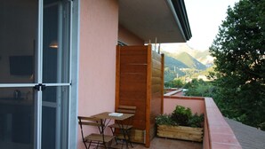 A balcony with a wooden table and chairs, a sliding glass door, and a view of mountains. - La Marmifera B&B (Carrara)