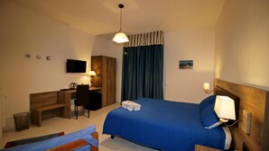 A hotel room with a bed, a desk, a chair, a TV, and a lamp. - La Marmifera B&B (Carrara)