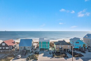 Une propriété située en bord de mer, comprenant une maison principale, une maison plus petite et une maison plus grande, toutes avec un accès direct à la plage.