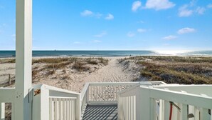 Une vue sur la plage depuis un escalier en bois menant à un bâtiment blanc.