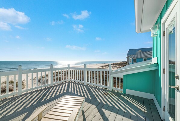 Une terrasse en bois avec une balustrade blanche donnant sur une plage.