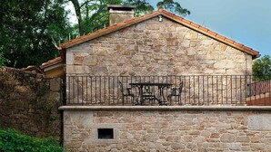 A stone building with a balcony, a small window, and a metal railing. - TWO ROOM APARTMENT (Laxe)