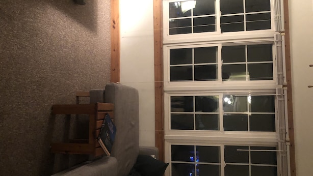 Ein Zimmer mit einem großen Fenster, einem Holzstuhl und einem Sofa.
