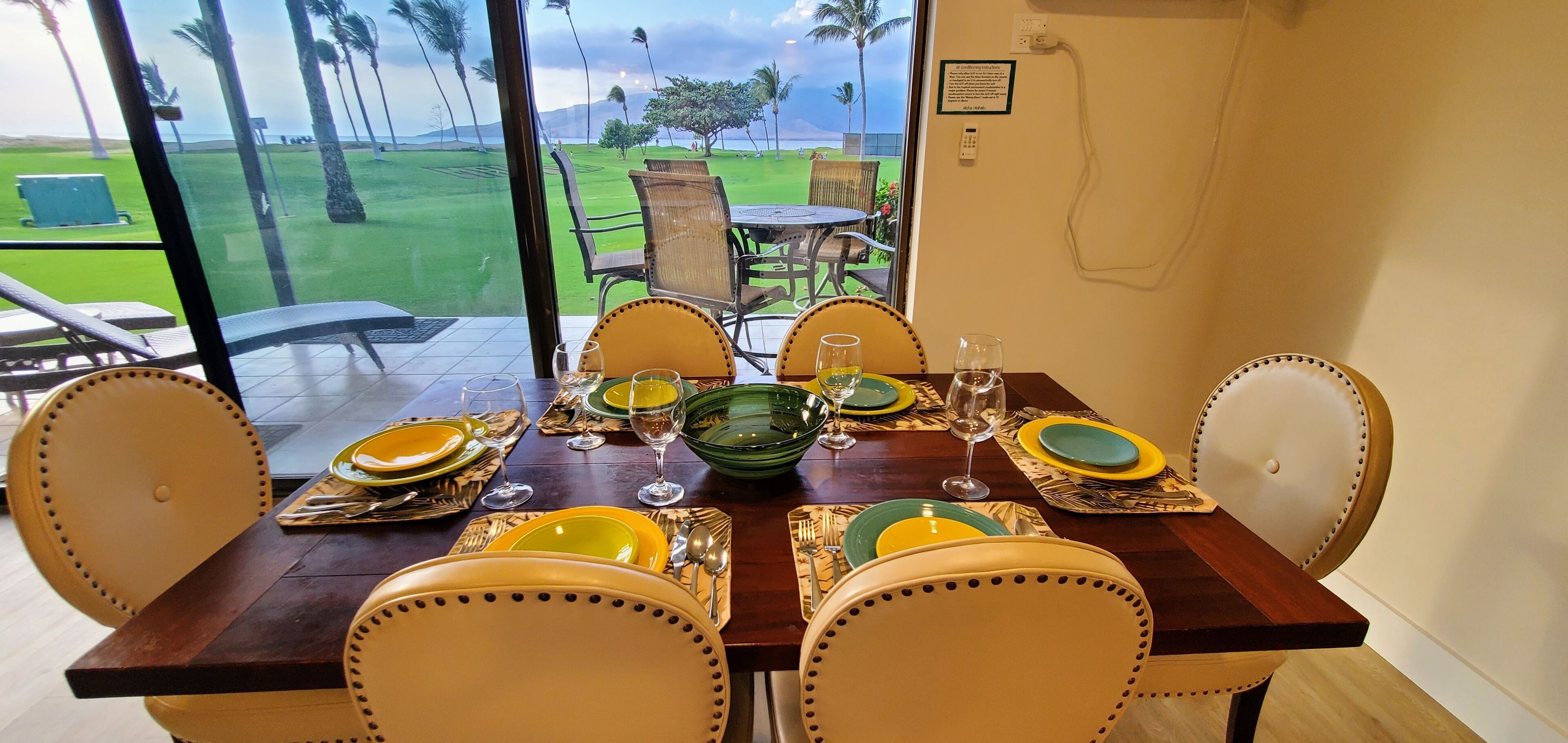 Een eettafel gedekt met borden, glazen en bestek, met uitzicht op een golfbaan.