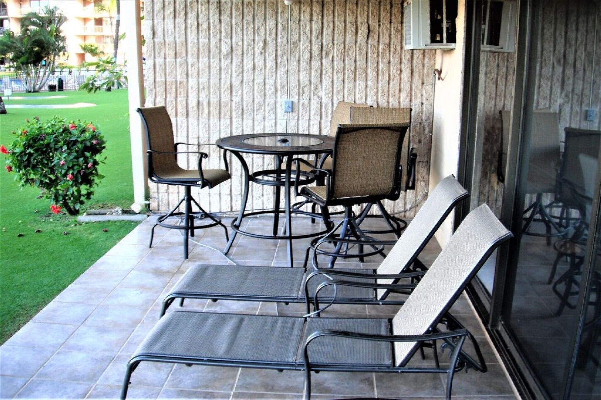 Un patio con una mesa redonda, dos sillas y dos sillones.
