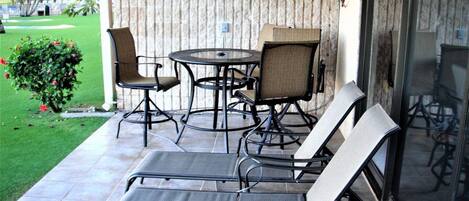 Un patio con una mesa redonda, dos sillas y dos sillones.