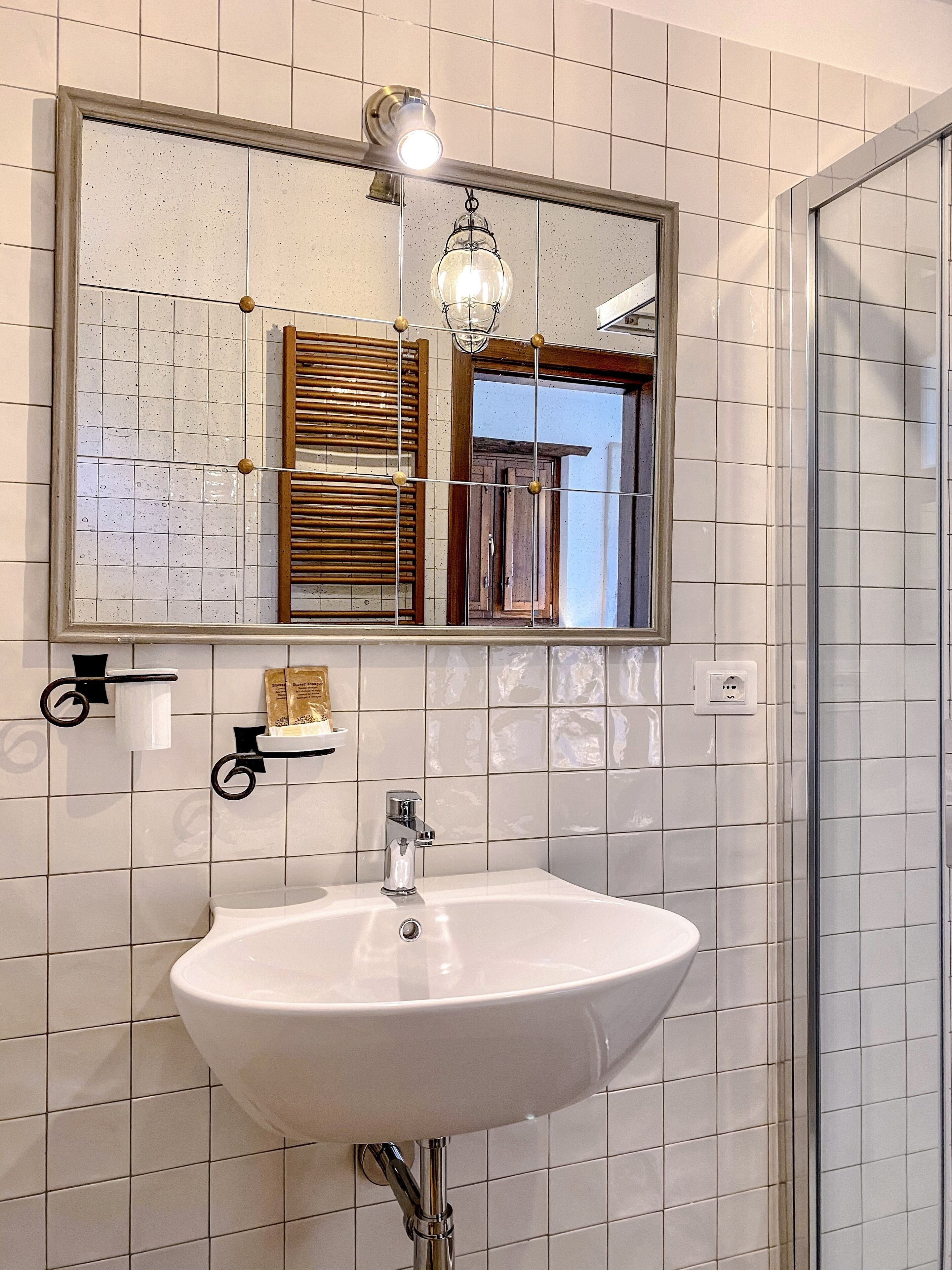 A bathroom with a white sink, a mirror above it, and a hanging light fixture.