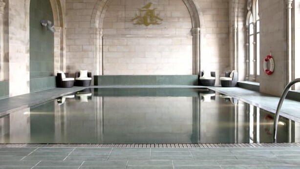 Una amplia piscina interior con paredes de piedra y arcos.