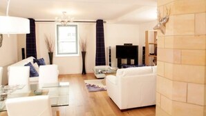 Una sala de estar moderna con un sofá blanco, una mesa de centro de vidrio y un televisor de pantalla plana.