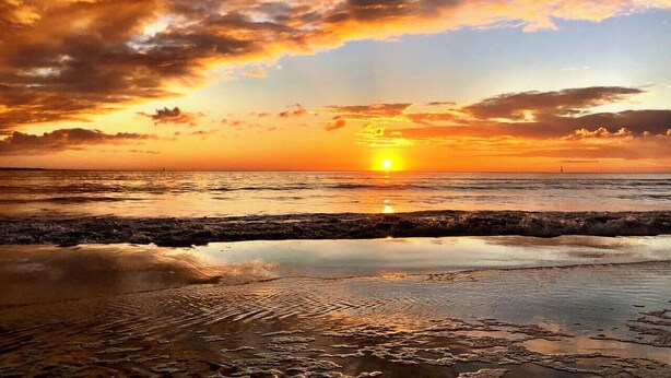 A beach scene with a sunset, waves, and a lighthouse in the distance. - SEAS THE DAY IS A PRIVATE 2BD COTTAGE WITH 3 COMMUNITY POOLS, PET FRIENDLY! (Port St Joe)