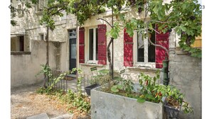 Une cour avec un mur en pierre, un banc et des plantes en pot.