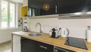 Une cuisine moderne équipée d’un évier, d’une machine à café et d’une bouilloire.