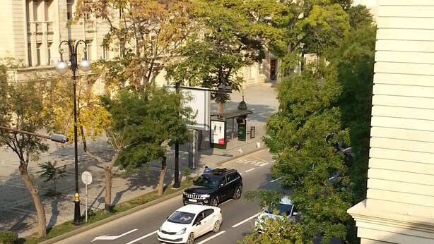 Vista di una strada con un attraversamento pedonale, veicoli e un edificio a architettura classica.