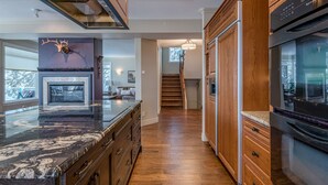Een moderne keuken met houten kastjes, een marmeren aanrecht en roestvrijstalen apparatuur.