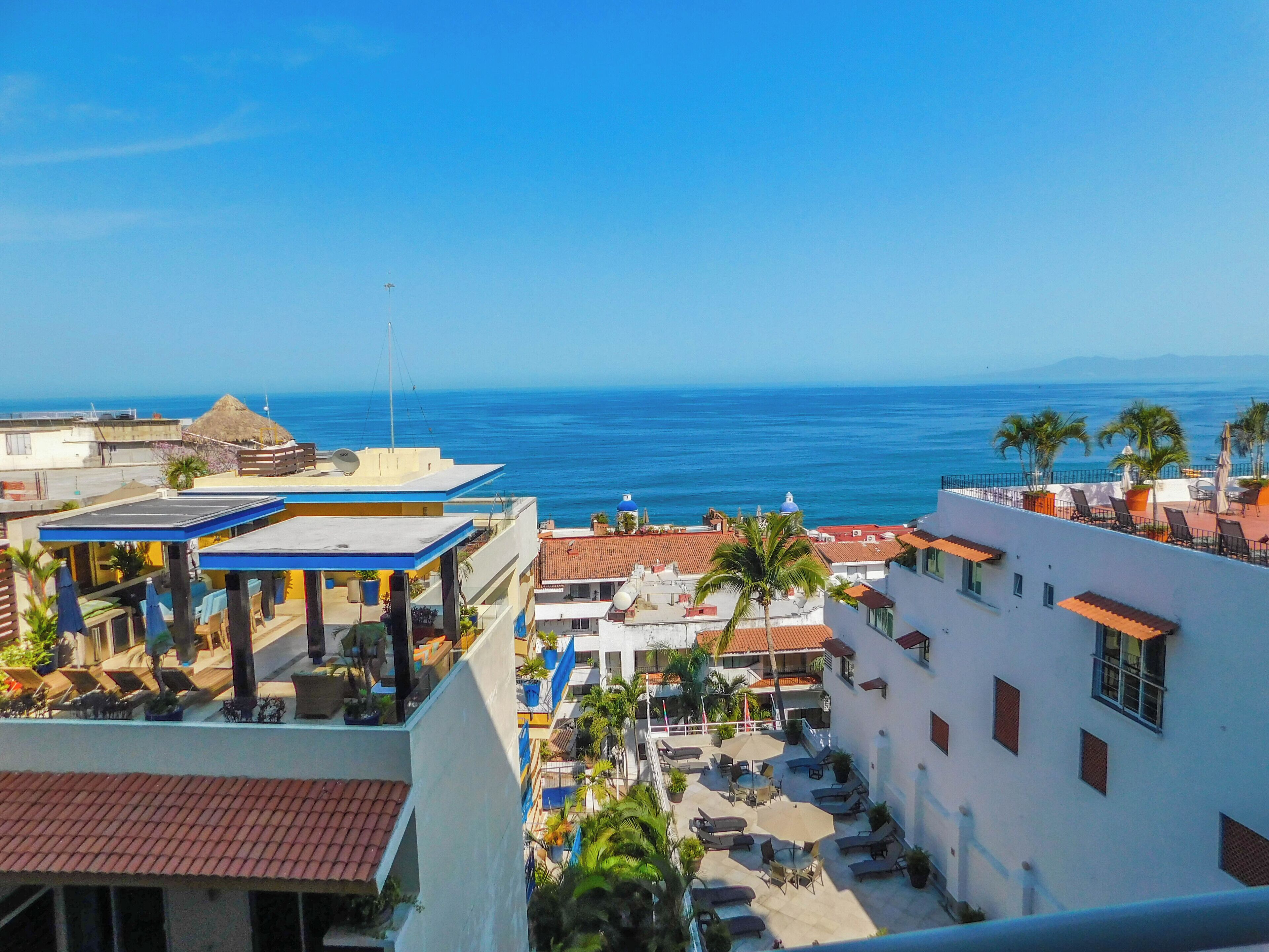 A rooftop bar with outdoor seating and a view of the ocean.